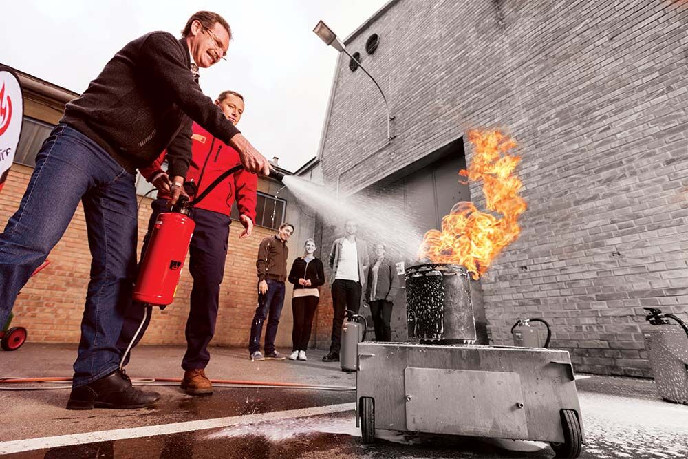 Teilnehmer im Brandschutzkurs beim Feuer löschen